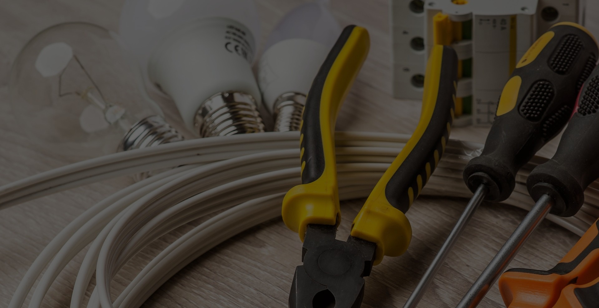 set of electrician tools, a coil of wire and equipment in background set of electrician tools, a coil of wire and equipment in background